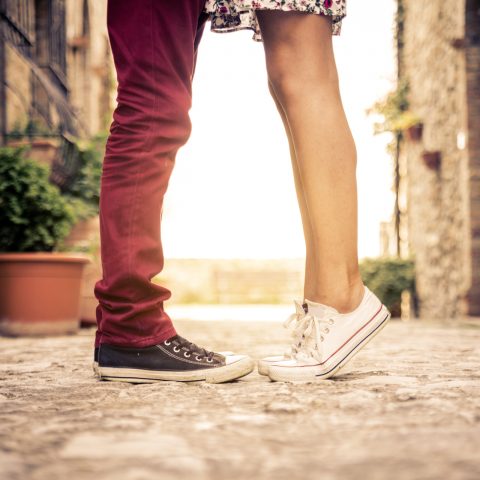 Couple standing on tip toes kissing
